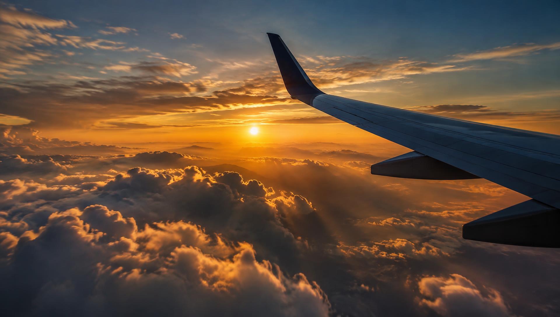 View of an airplane wing above golden sunset clouds